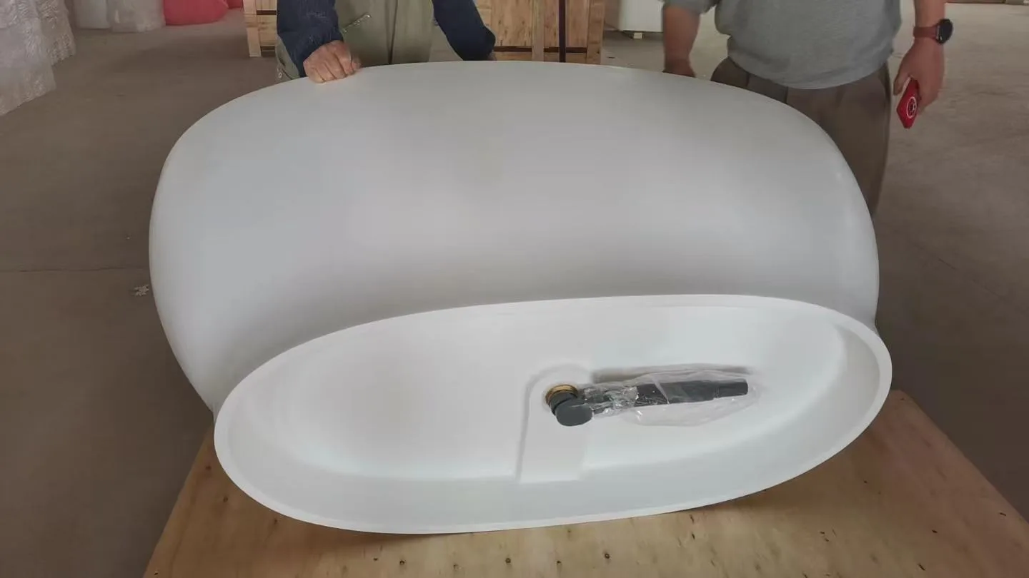 Side profile of a monolithic matte white freestanding solid surface bathtub resting on a factory wooden shipping pallet.