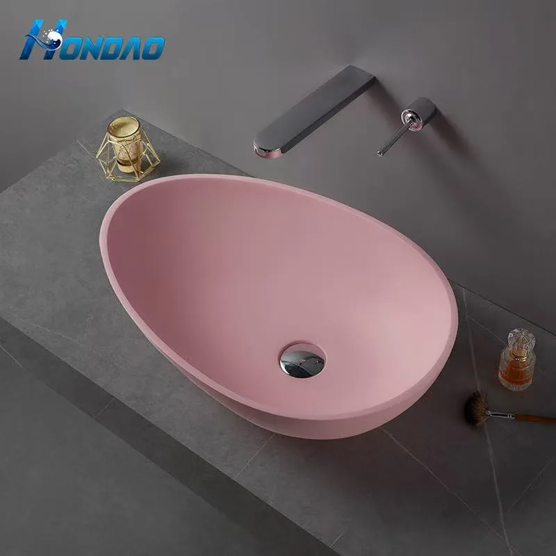 Front view of an asymmetrical pink solid surface countertop basin resting on a minimalist grey stone vanity.