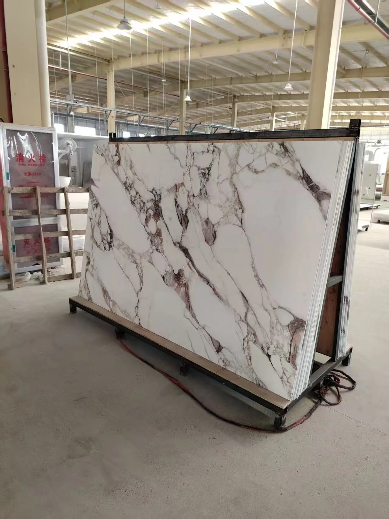 Factory storage of large-format solid surface shower panels ready for commercial hospitality installation.