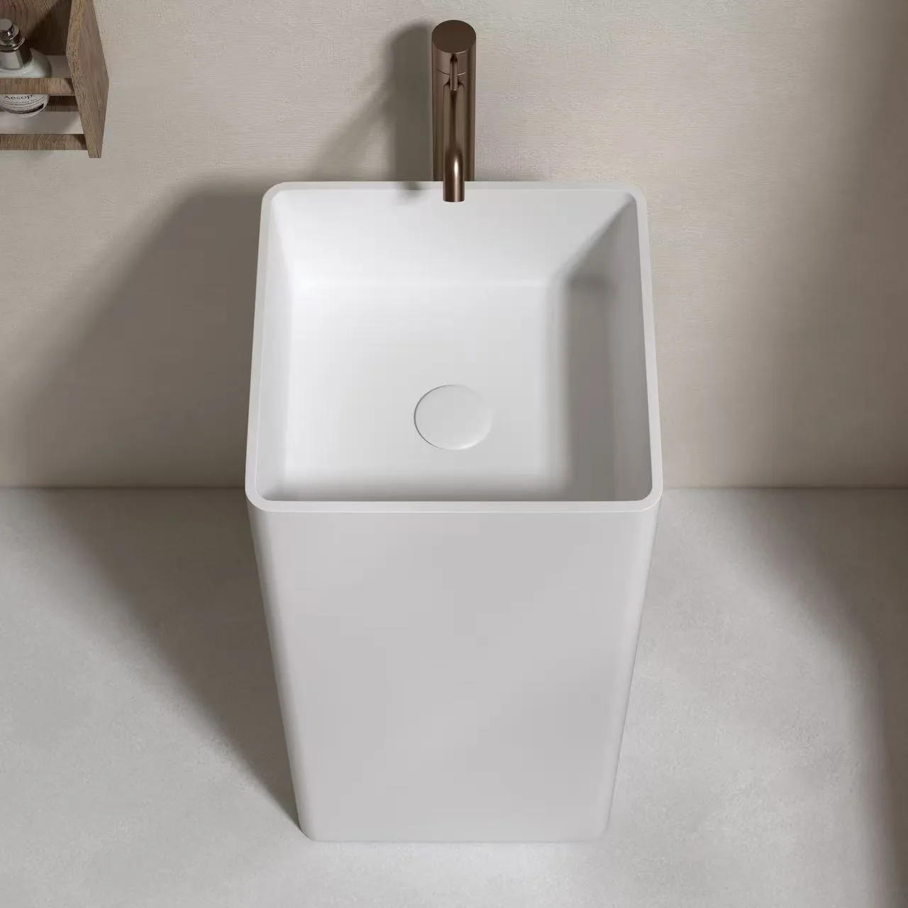 Top-down perspective of a homogenous square pedestal sink showing the integrated basin depth and seamless commercial drain cover.