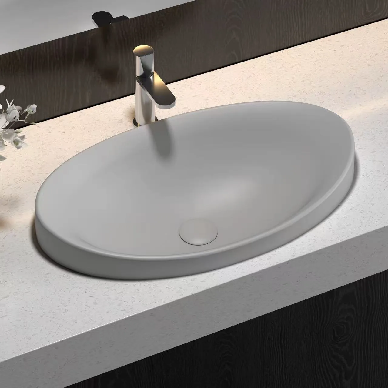 Matte dark grey oval solid surface sink installed on a terrazzo commercial vanity in a boutique hotel.