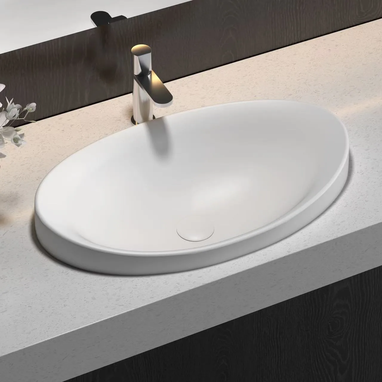 Top-down perspective of an oval solid surface sink resting seamlessly on a custom wood hospitality cabinet.