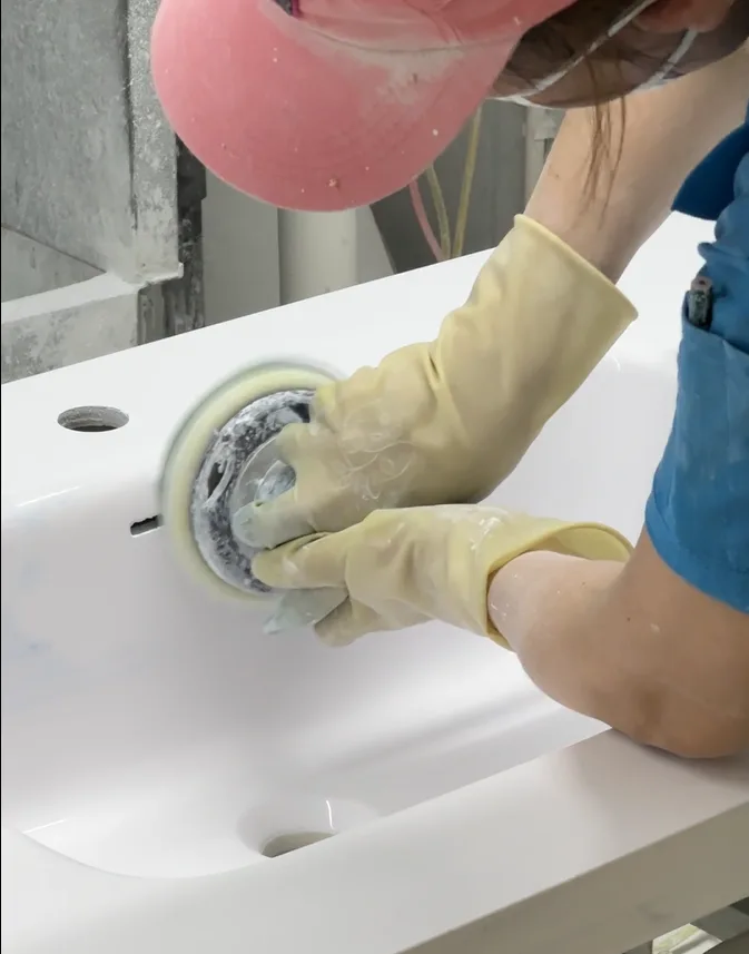 HONDAO factory technician meticulously hand-polishing the drain recess of a custom solid surface sink to ensure flawless commercial drainage.