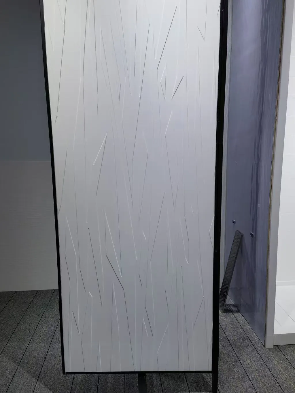 Physical sample of 3D Cultured Marble Shower Panels featuring an abstract geometric line pattern.