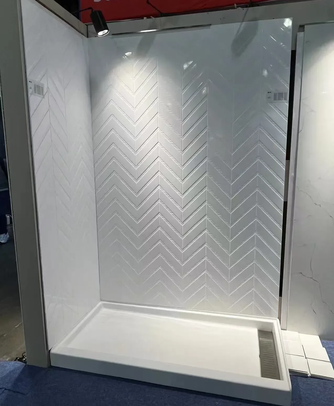 Grout-free 3D Artificial Stone Shower Wall Panels with chevron texture displayed in a showroom.