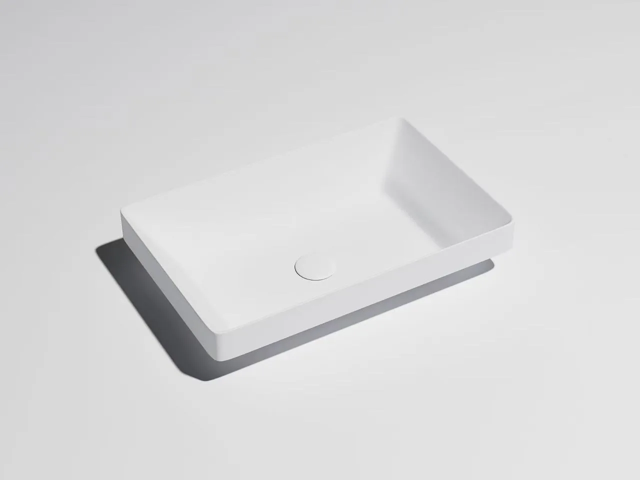 Minimalist matte white solid surface thin-edge vessel sink designed for high-end hospitality washrooms.