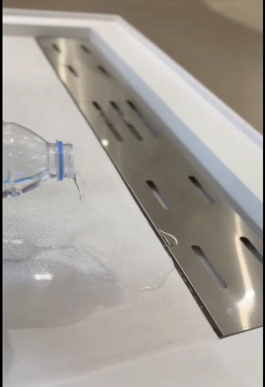 Water fluid testing over an integrated linear stainless steel drain channel built into an Artificial Stone Shower Base.