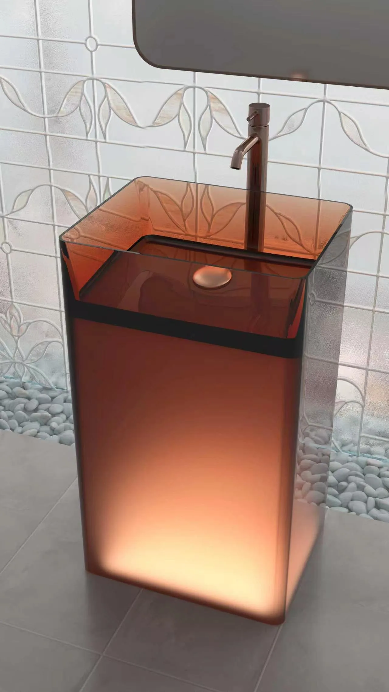 Three-quarter perspective view of the amber illuminated translucent resin pedestal washbasin integrated with a matching rose gold faucet against a decorative glass block wall.