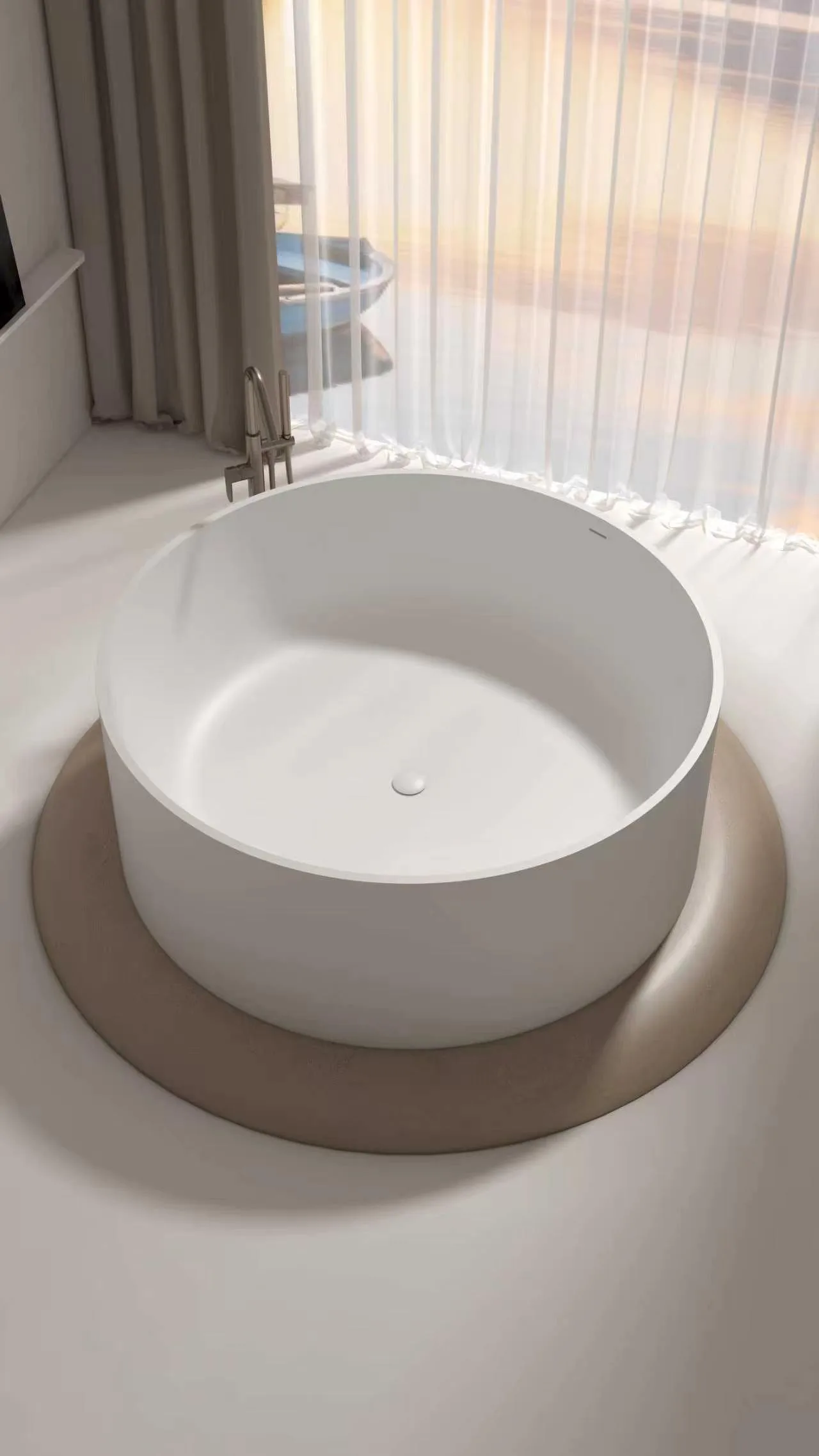 Close-up high-angle view emphasizing the perfectly circular geometric silhouette and central matching pop-up drain of the matte white round solid surface freestanding bathtub.