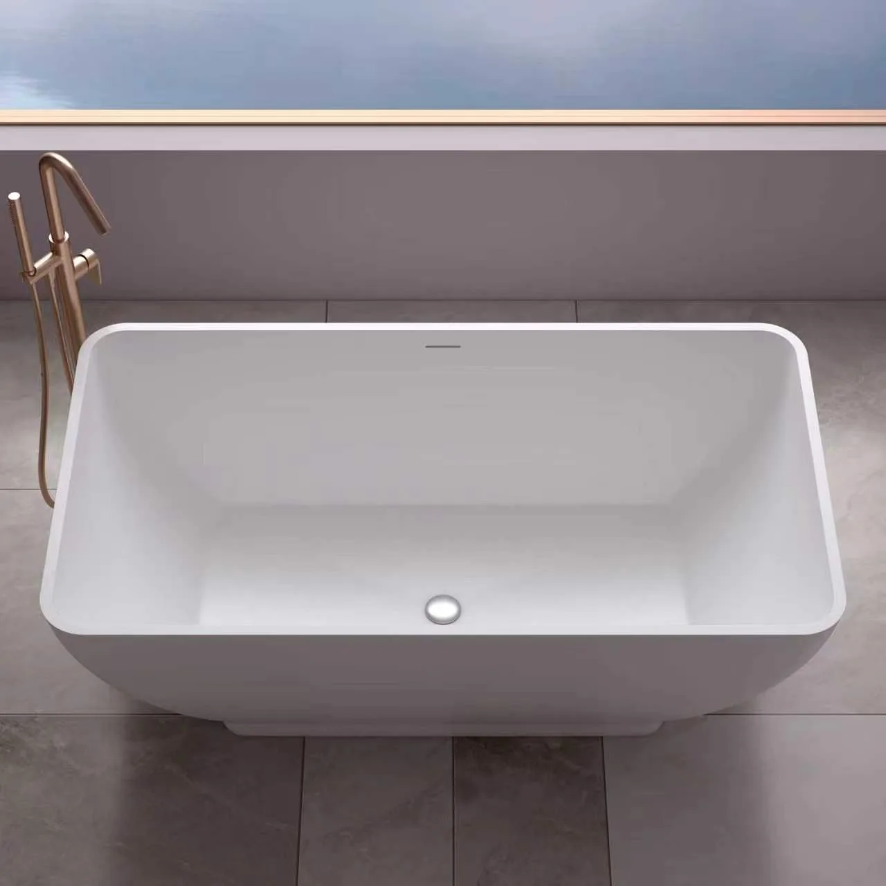 Direct high-angle top-down view looking into the clean interior basin of the matte white tapered solid surface freestanding bathtub, highlighting its crisp rectangular rim and centered pop-up drain.