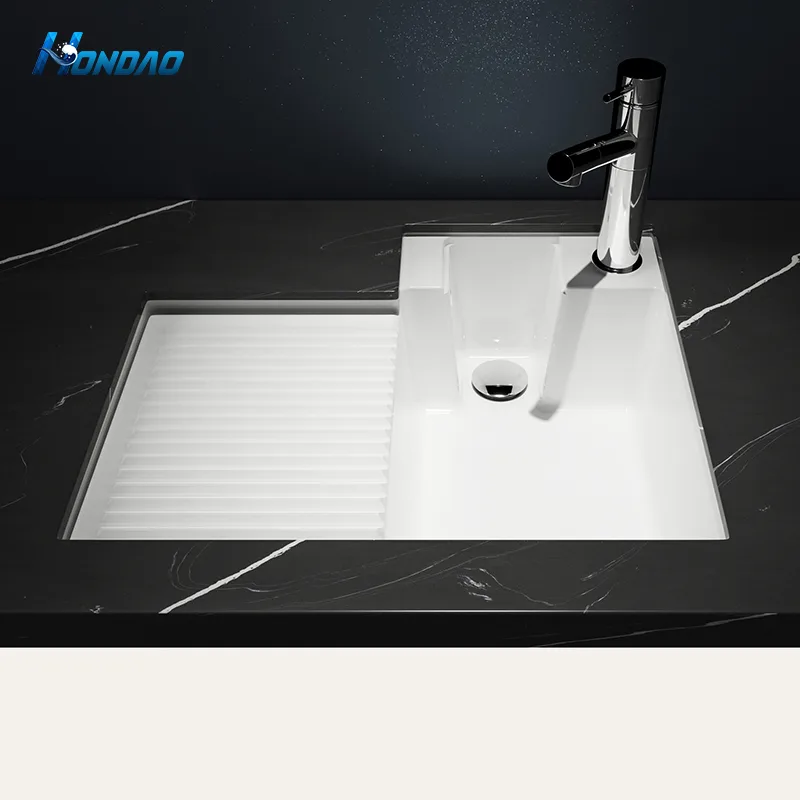 Matte White Solid Surface Laundry Sink with Washboard for Commercial Hospitality Projects undermount installation view in a black quartz countertop paired with a tall chrome faucet.